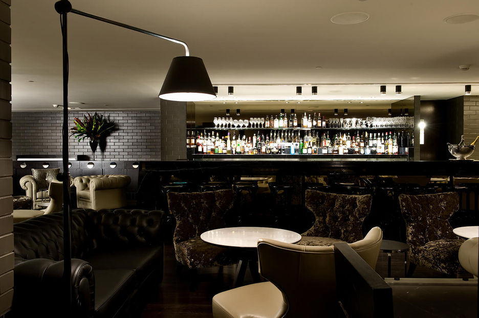 Interior photography of a moody restaurant dining layout with a black dome hanging light casting a warm glow over a round table.