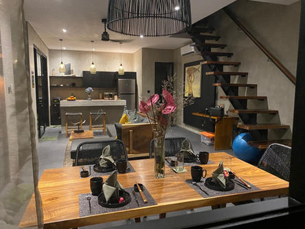 "Zen Villa in Canggu: A serene oasis with a spacious living room, kitchen area adorned in earthy, natural colors, and modern wooden furniture. and a large wooden dining table