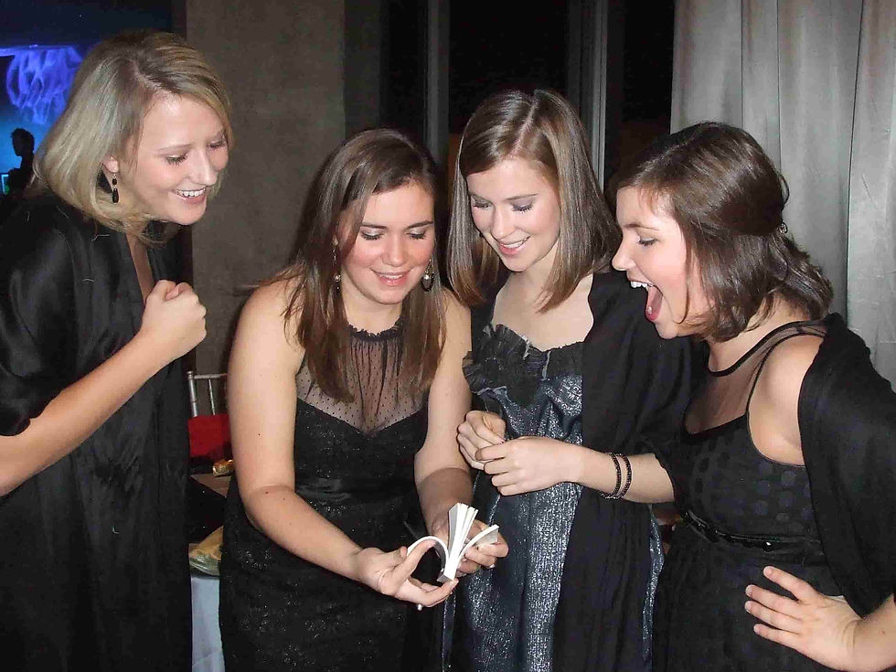 Four women in black dresses gather excitedly around watching a flip book come to life.