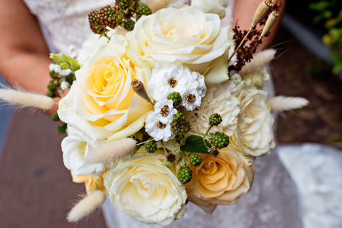 A classic yellow and white bridal bouquet, held by an American bride in her wedding dress during a Catholic wedding in Amsterdam.