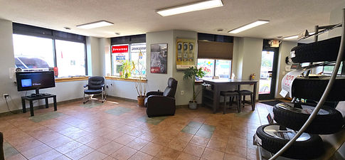Customer waiting area at Grand Rapids Tire & Auto featuring a message chair, television, table, candy and service desk