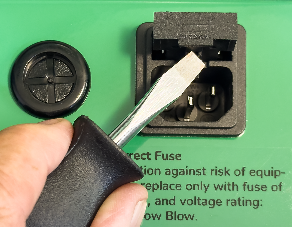 Using a flat-head screwdriver to pull the fuse holder from a Schaffner power entry module