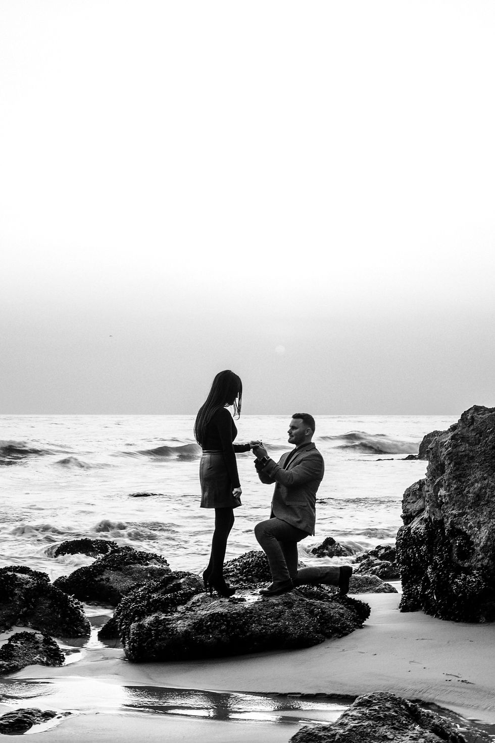 Black and white couple during a romantic beach proposal at sunset.