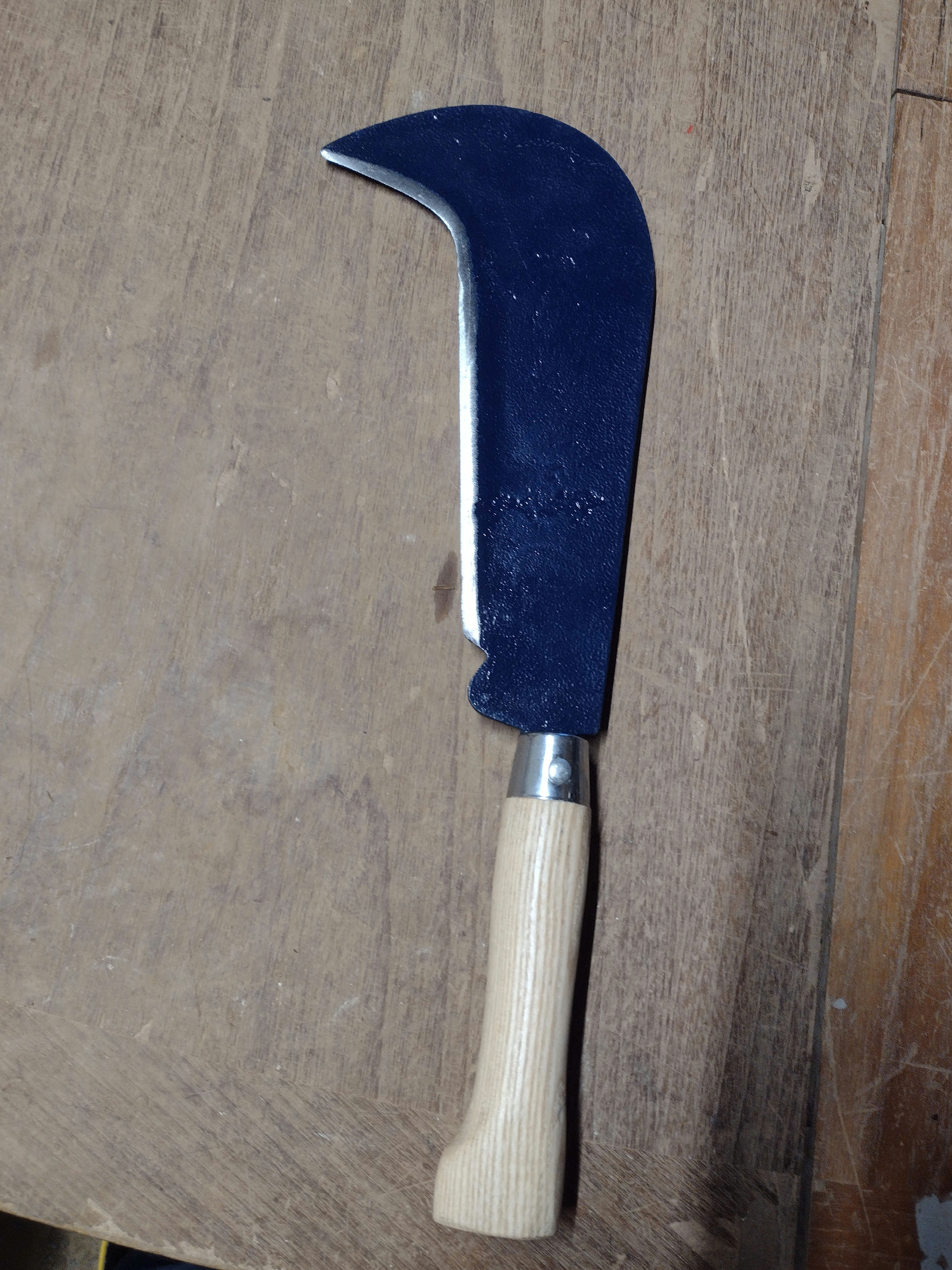 A curved, blue-painted hand sickle with a light wooden handle