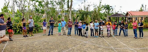 Imagen de personas ubicados en circulo realizando una dinámica guiada de diálogo,post huracaán María en un espacio abierto, piso de piedra y rodeado de naturaleza