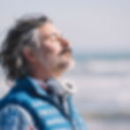 man sideways on taking a deep breath in the wind. Breathing practice helps with stamina, endurance and wellbeing.