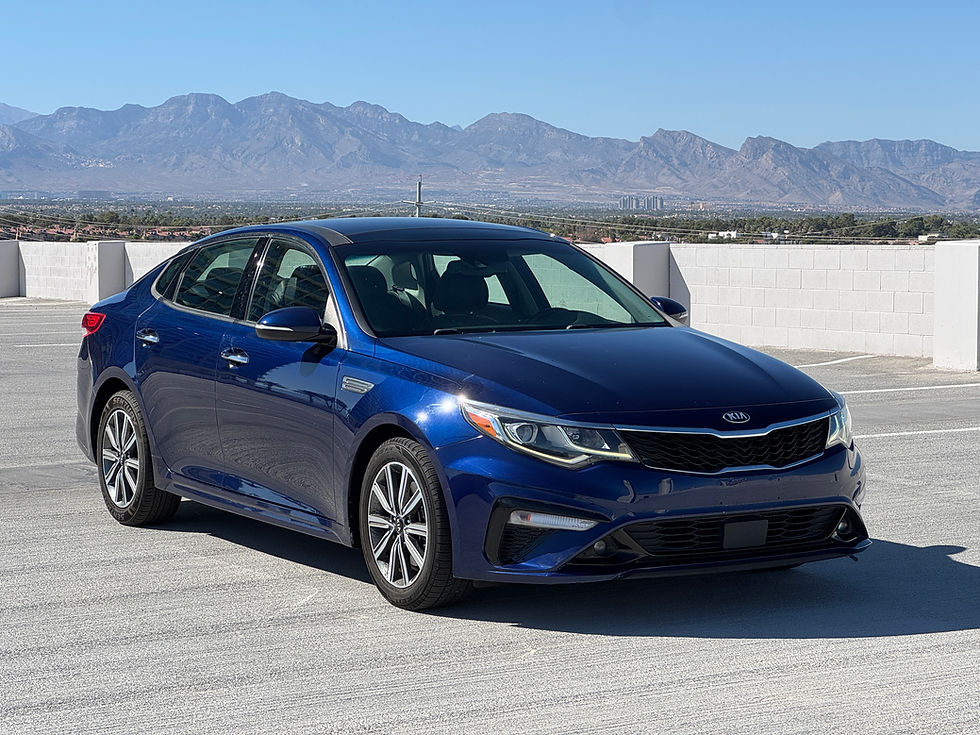 Blue Kia car parked on a rooftop with distant mountains and a clear blue sky. No visible text. Peaceful, sunny day.