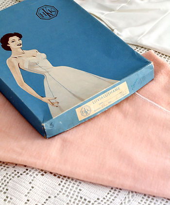 Vintage liivialushamelaatikko ja villaiset puolialushousut virkatun pöytäliinan päällä