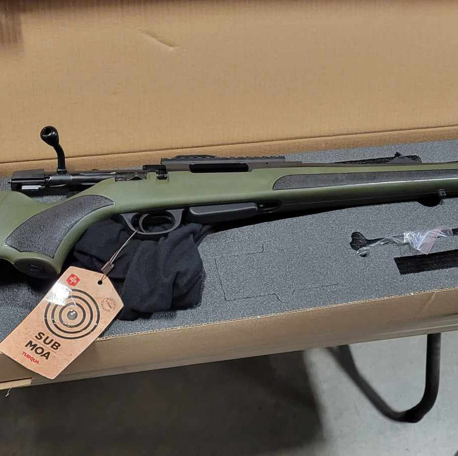 Green and black bolt-action rifle in shipping box