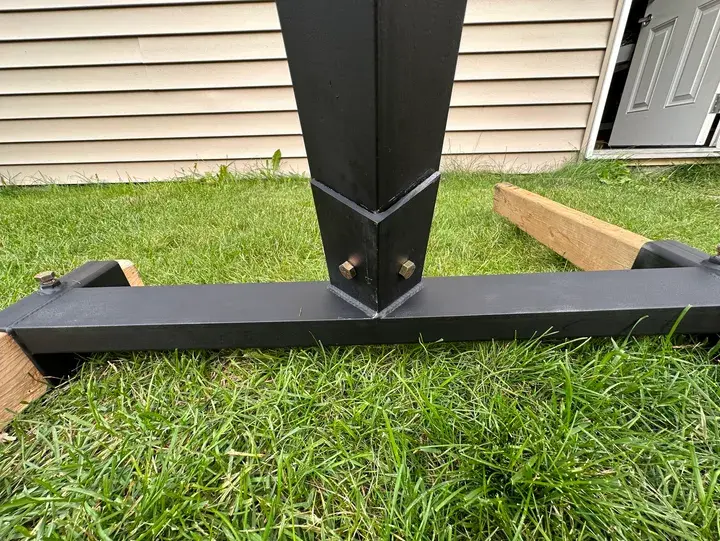 Black metal support bolted to a base, on grass
