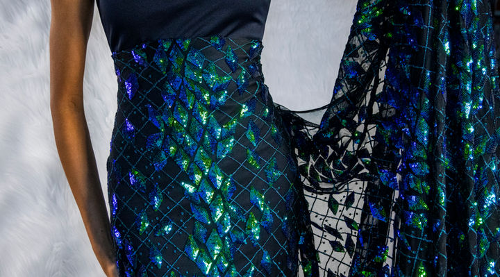 Mujer posando con un textil de encaje transparente con destellos azules y transparente