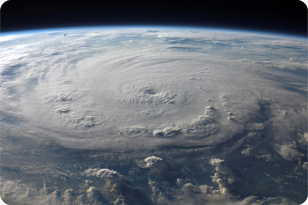 A vast hurricane swirls over the Earth, seen from space. Thick white clouds form a spiral pattern against a deep blue background.