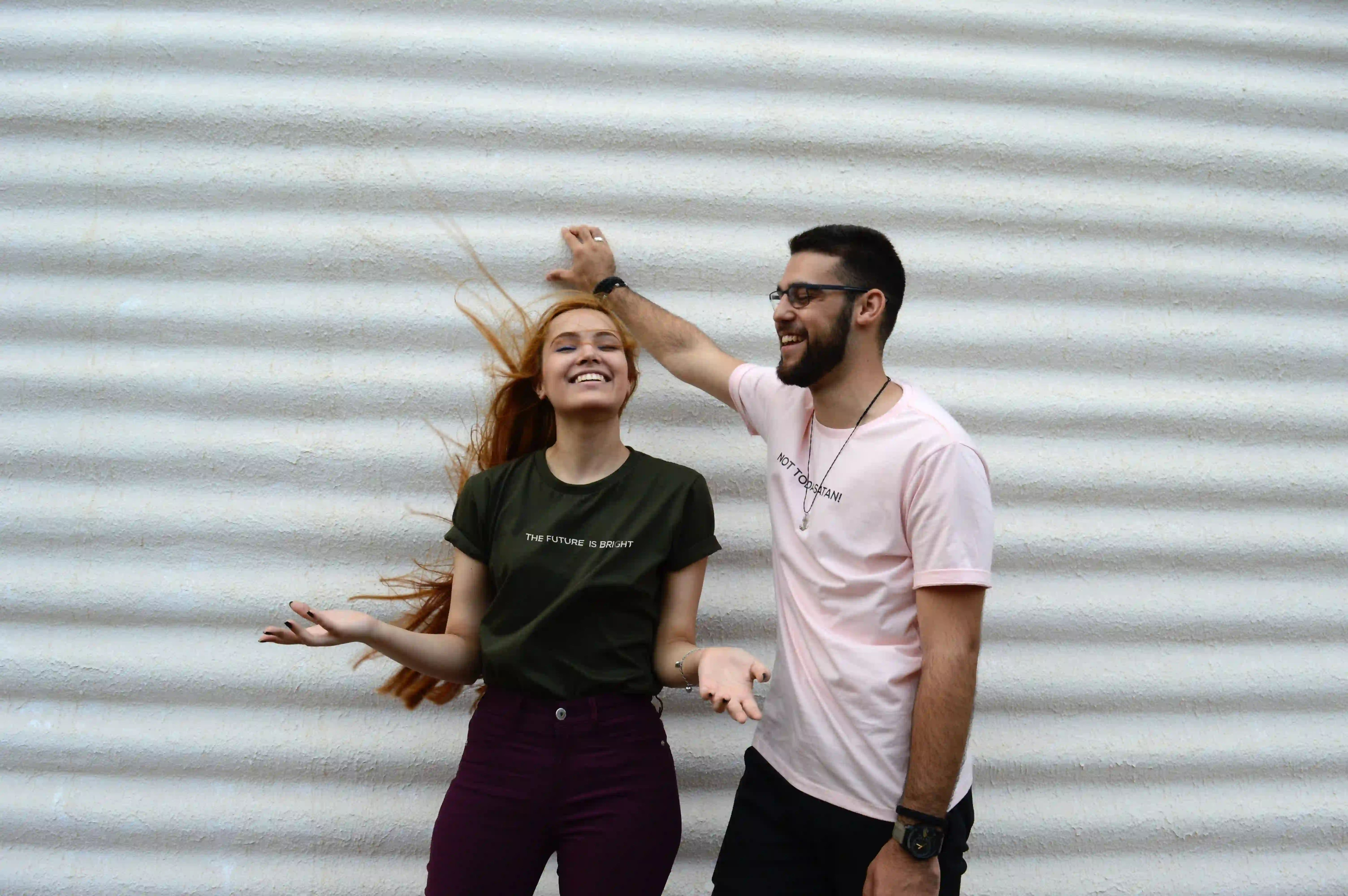 A man and woman influencers posing in front of a white wall.	