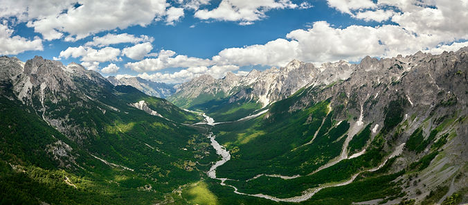 Panoramic, aerial view of the scenic Valbona river valley, green valleys, blue sky with cl