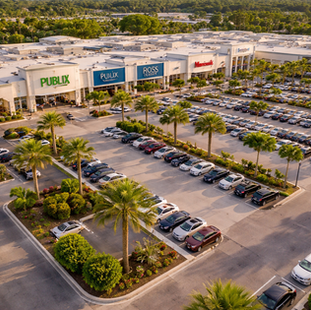 Aerial view of a busy open-air retail shopping center with parking and national tenants, illustrating real estate investment and asset performance.