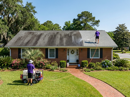 Professional soft washing a roof on a brick home in Wilmington NC to safely remove algae and dark streaks