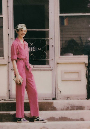 Image of a woman in pink standing on steps in front of a house