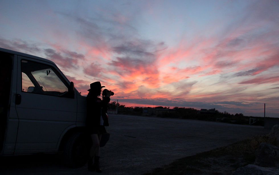 Une femme photographe devant son Van au soleil couchant;