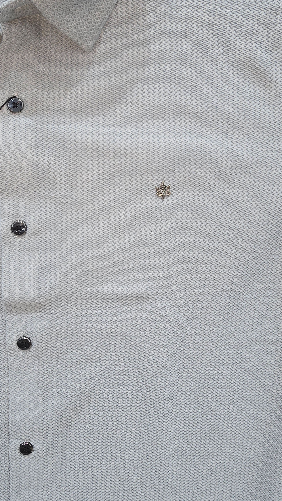 Light gray textured fabric with dark buttons and leaf logo