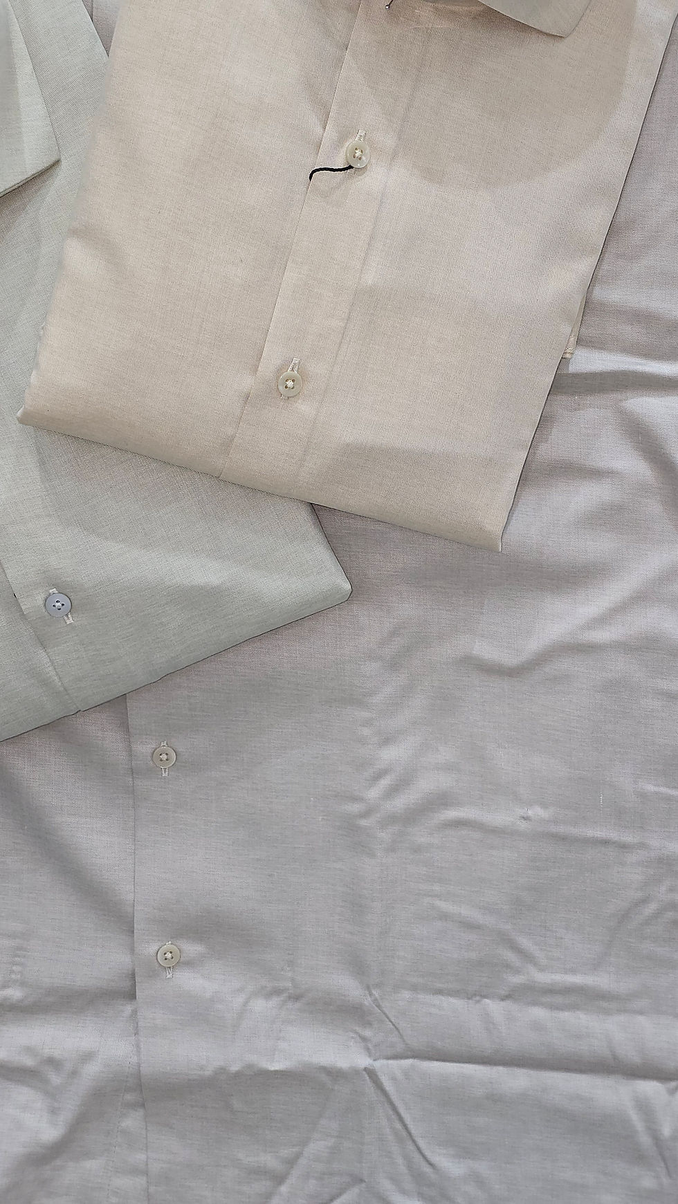 Two folded shirts, one beige, one light grey