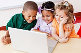 three young children learning in front of a laptop computer
