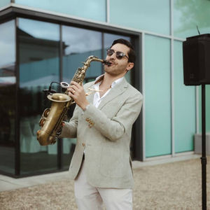 Saxophonist zum Sektempfang neben einer Musikanlage in grünem Sakko