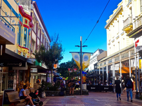 Street photography, colourful shops and pedestrians on Cuba Street, Wellington New Zealand, sunny day with a clear blue sky, vibrant and lively