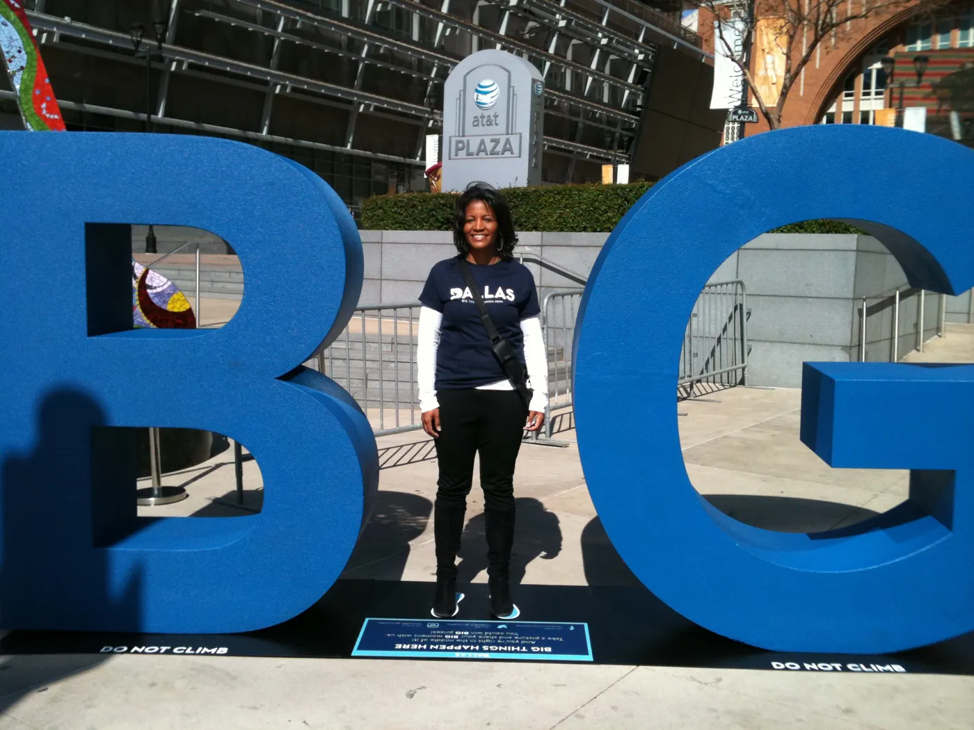 Noelle LeVeaux standing between giant blue B and G letters from the Dallas BIG campaign at AT&T Plaza