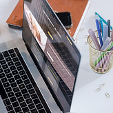 Open laptop showcasing a wesbite with some pens and a notebook in the background