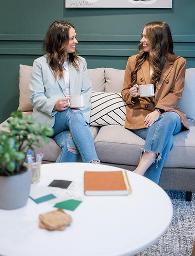 Two Starts with B owners, a startegist and a designer, sitting on a couch laughing and drinking coffee