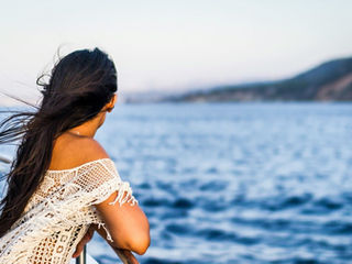 A woman on a cruise ship looks toward the shore