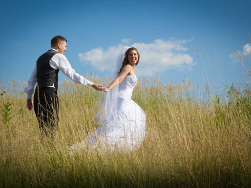 Bride pulls her groom through a grassy field at a golf course