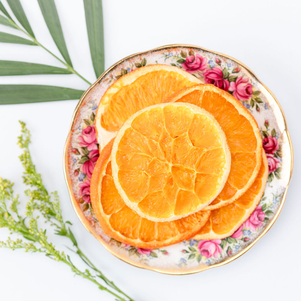 Dried orange slices displayed on an antique pink and gold floral serving plate.