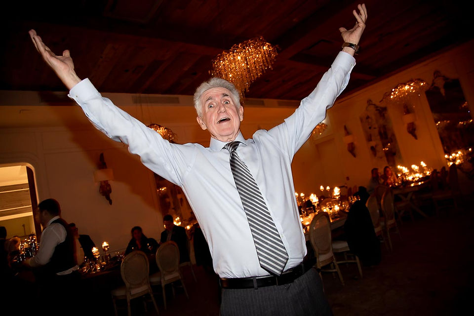 A man with his arms outstretched dancing during a wedding reception at Elora Mill.