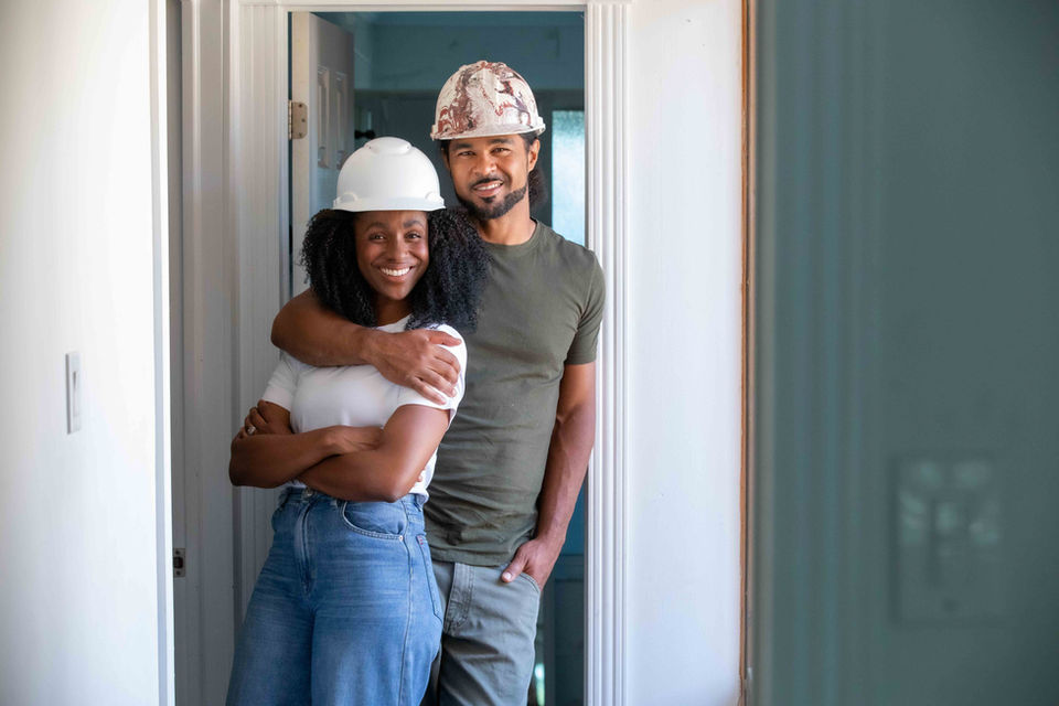 Gut Job Season 2 of Seb Clovis and Ayanna Augustine wearing hard hats smiling at camera, by LBLstudio.
