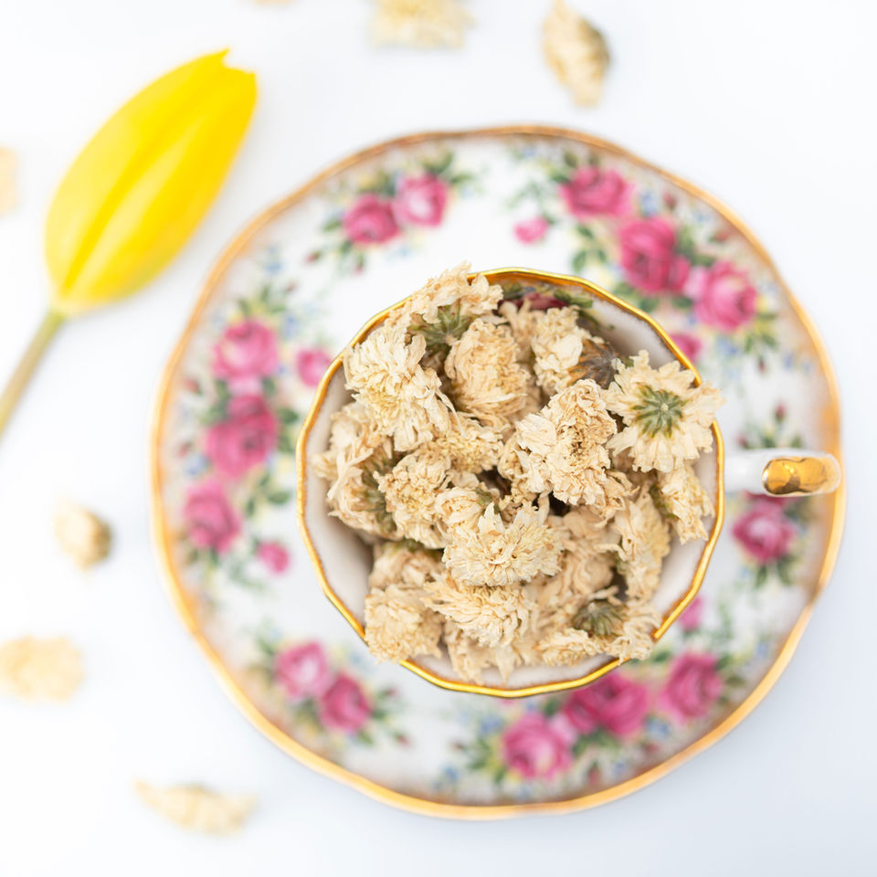 Loose leaf camomile presented in a gold and pink floral tea cup set.