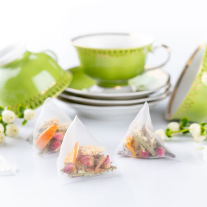 Antique green and gold teacups surrounded by hand made tea filled with luxury flowers and herbs.