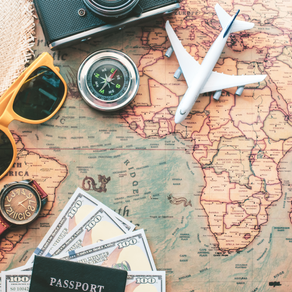 Old school map with traveling items on top of it like yellow sunglasses, a compass, a toy airplane, a watch, a beach hat, a passport with hundred dollar bills inside of it