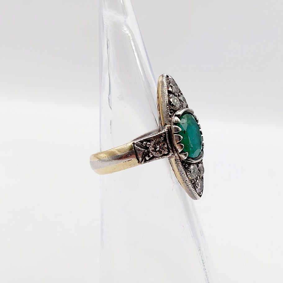 Bague ancienne en or et argent, ornée d'émeraudes et diamants, sur fond blanc.