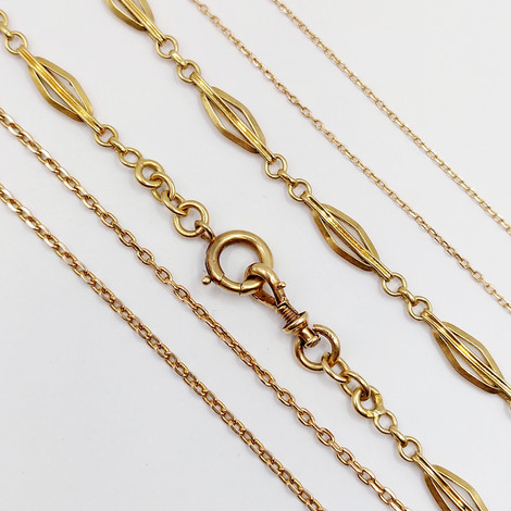 Plusieurs colliers dorés, chaînes fines et ornées, sur fond blanc, détails rapprochés.