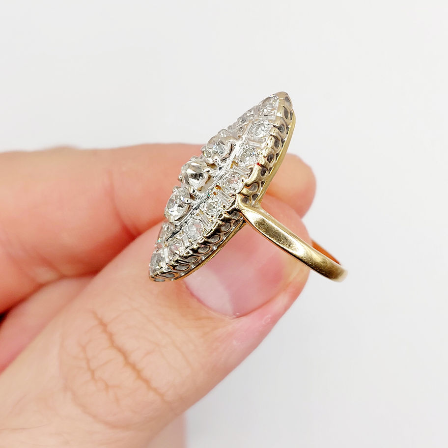 Main de femme tenant une bague marquise antique 18k et diamants taille ancienne.