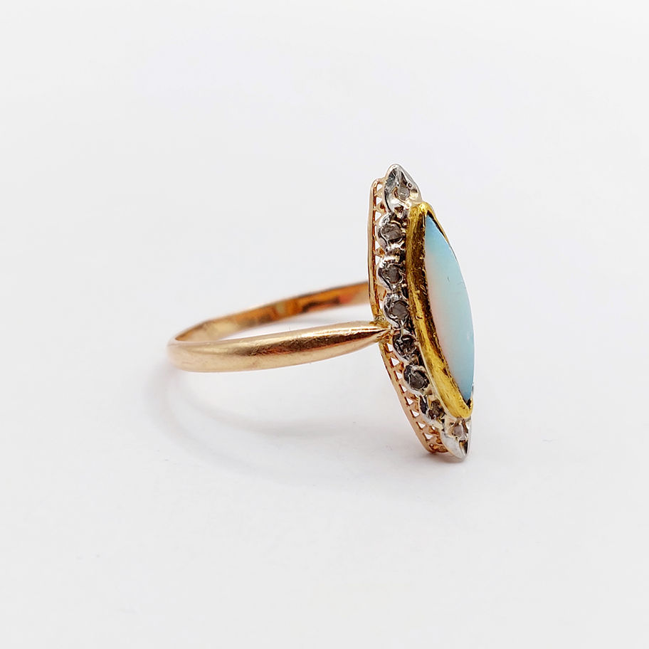 Bague en or avec opale et diamants, vue latérale, sur fond blanc.
