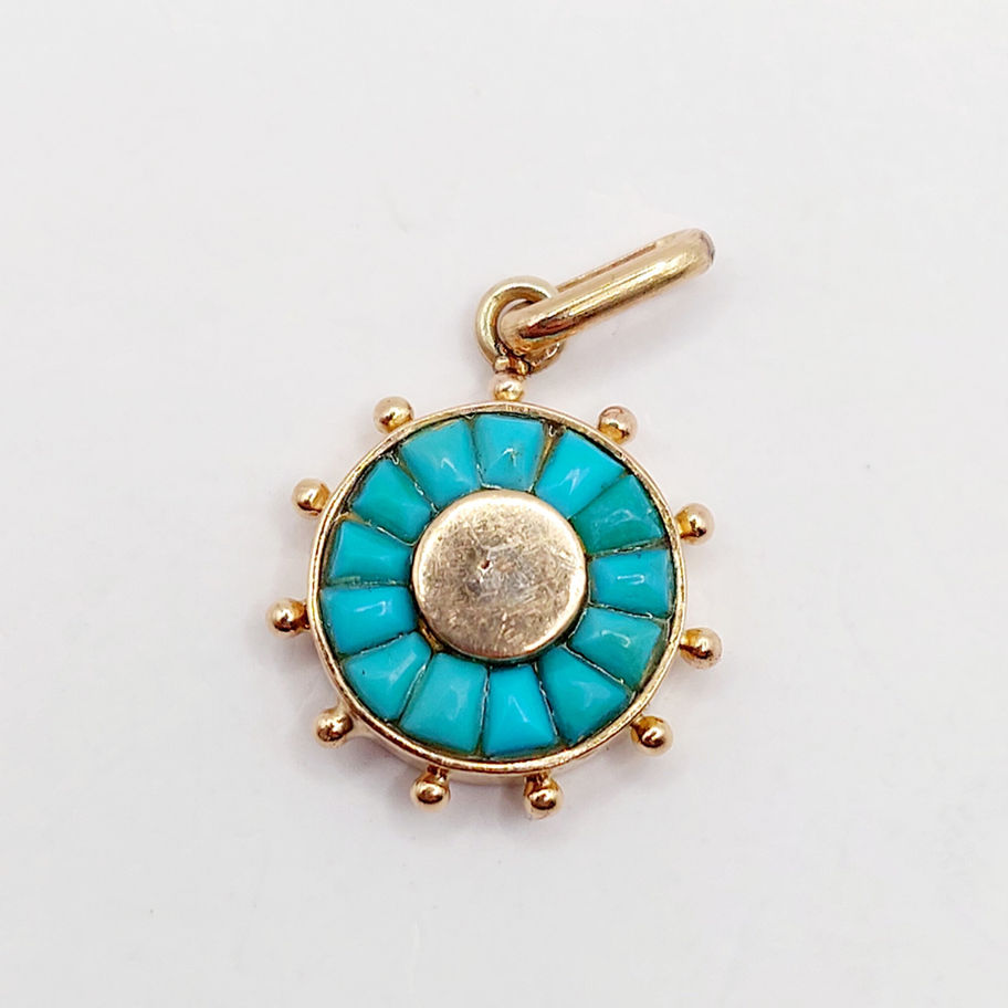 Pendentif rond en or avec turquoise bleue, sur fond blanc, bijou unique.