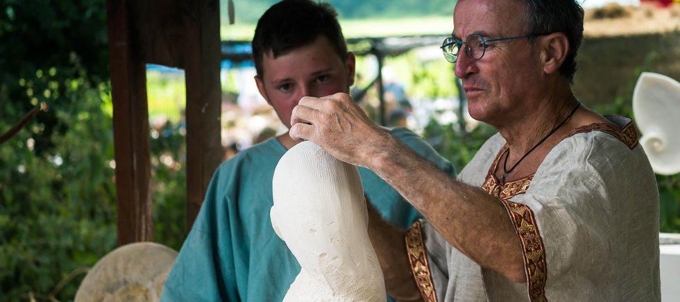 Un tailleur de pierre et son apprenti face à un morceau de pierre blanche. 