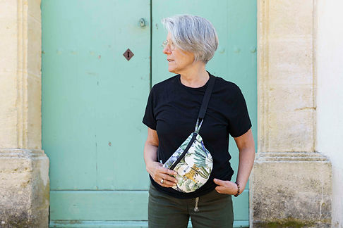 La créatrice portant un sac banane devant la porte de son atelier