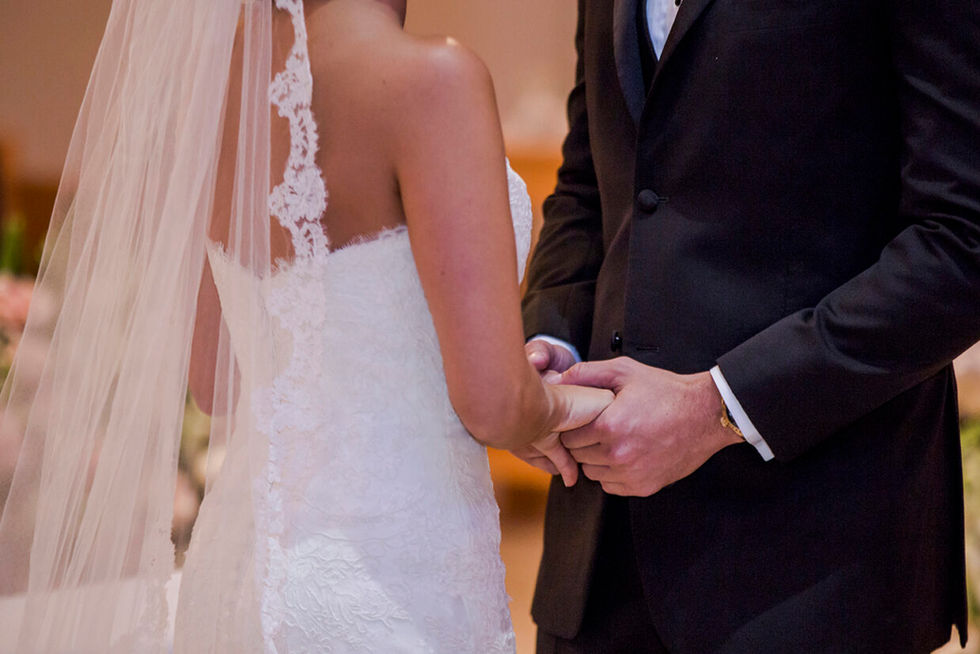 Bride and groom hold hands during wedding ceremony