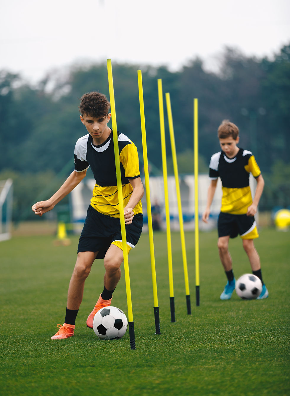 Young Football Players Running Slalom and Dribbling With Balls Between Training Poles Socc