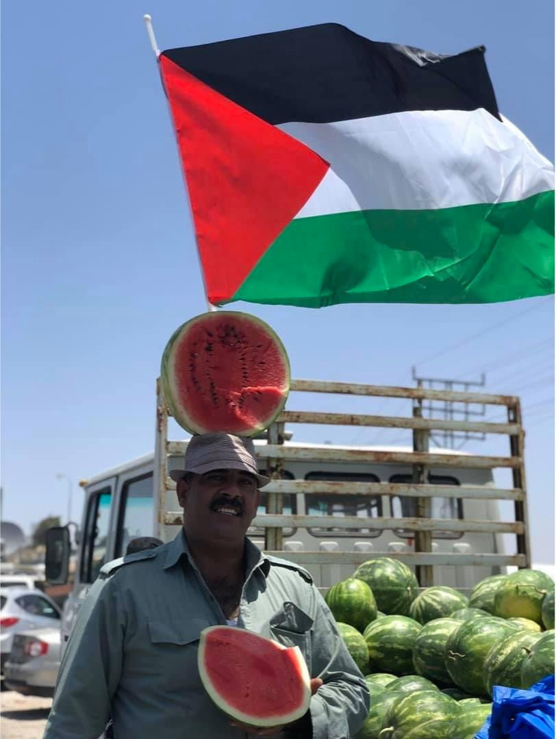 A Palestinian man holding a watermelon with the Palestinian flag