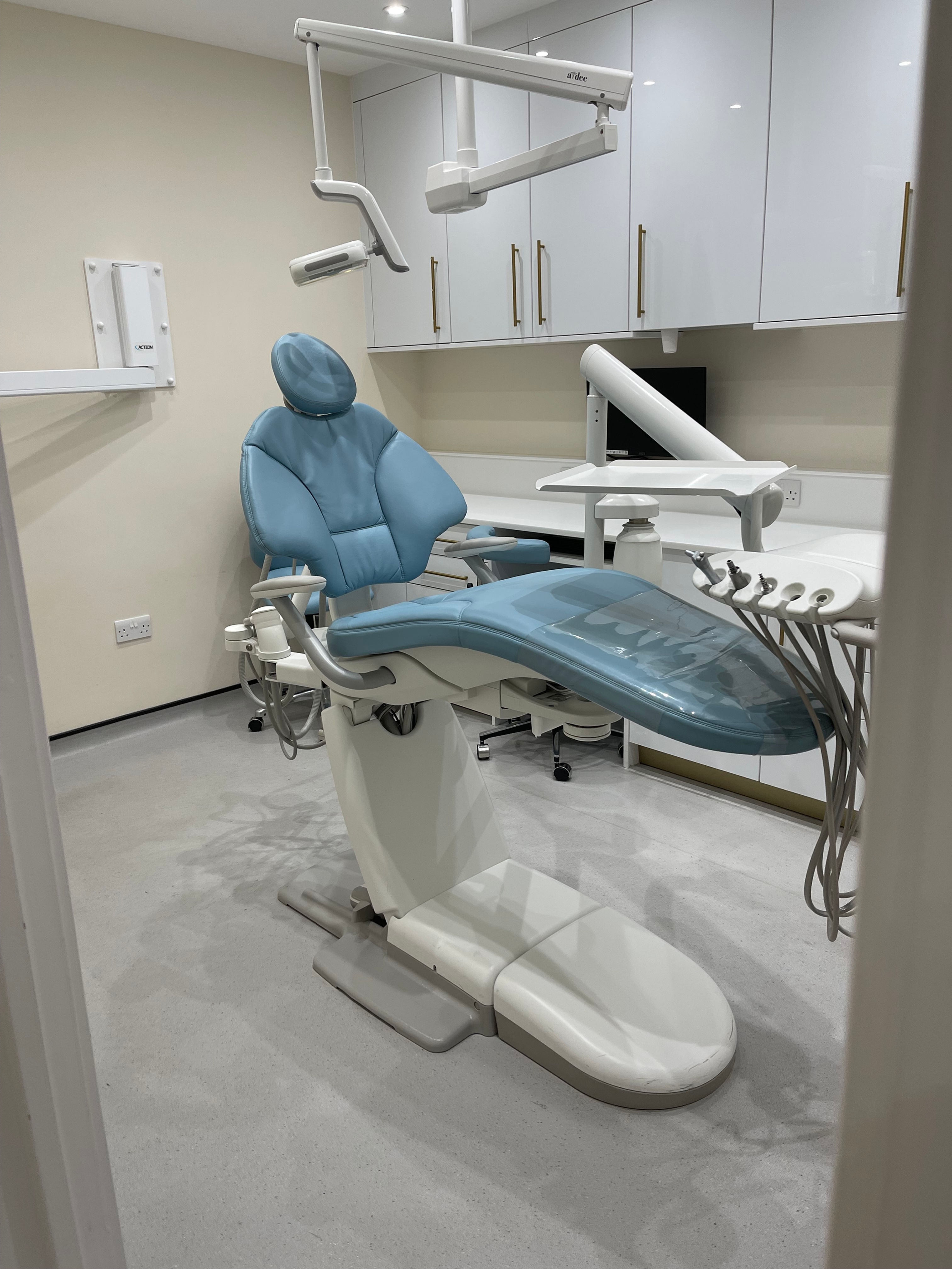 Clean dental office with a blue dental chair and overhead light