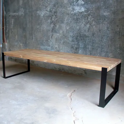 Side profile of industrial-style teak dining table showing slim black iron legs and sun-bleached solid wood top.